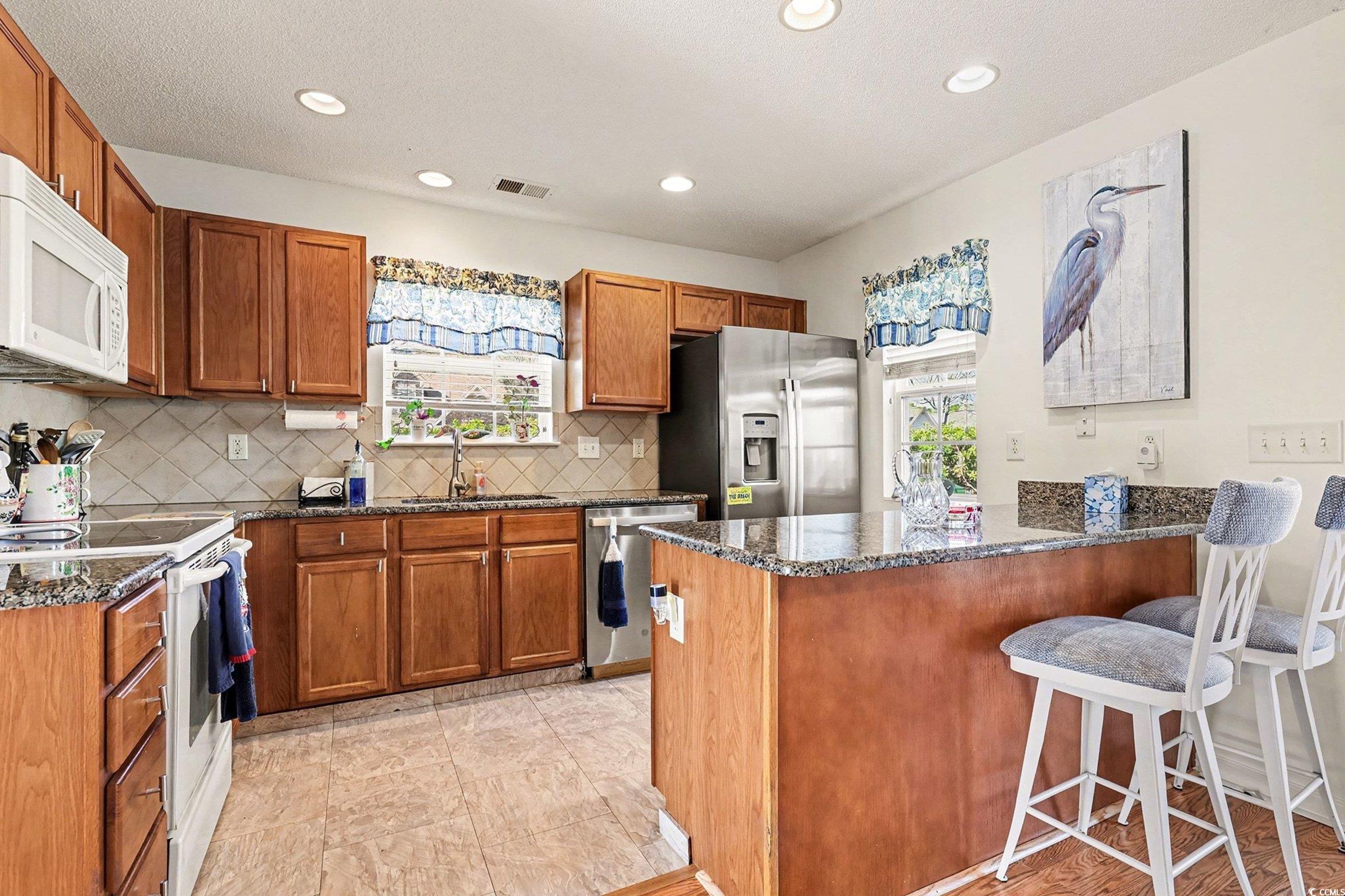 844 Sheridan Road, Unit 844 Myrtle Beach, SC 29579 - Photo 3 of 24 Kitchen with brown cabinets, a breakfast bar, dark stone counters, stainless steel appliances, and recessed lighting