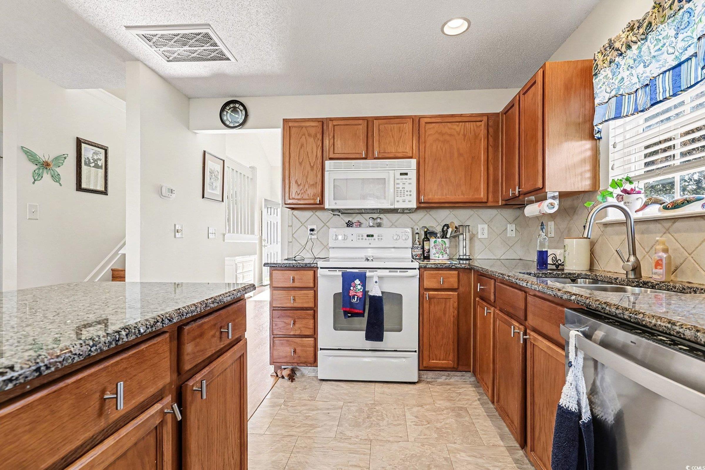 844 Sheridan Road, Unit 844 Myrtle Beach, SC 29579 - Photo 10 of 24 Kitchen featuring brown cabinets, white appliances, dark stone countertops, and a textured ceiling
