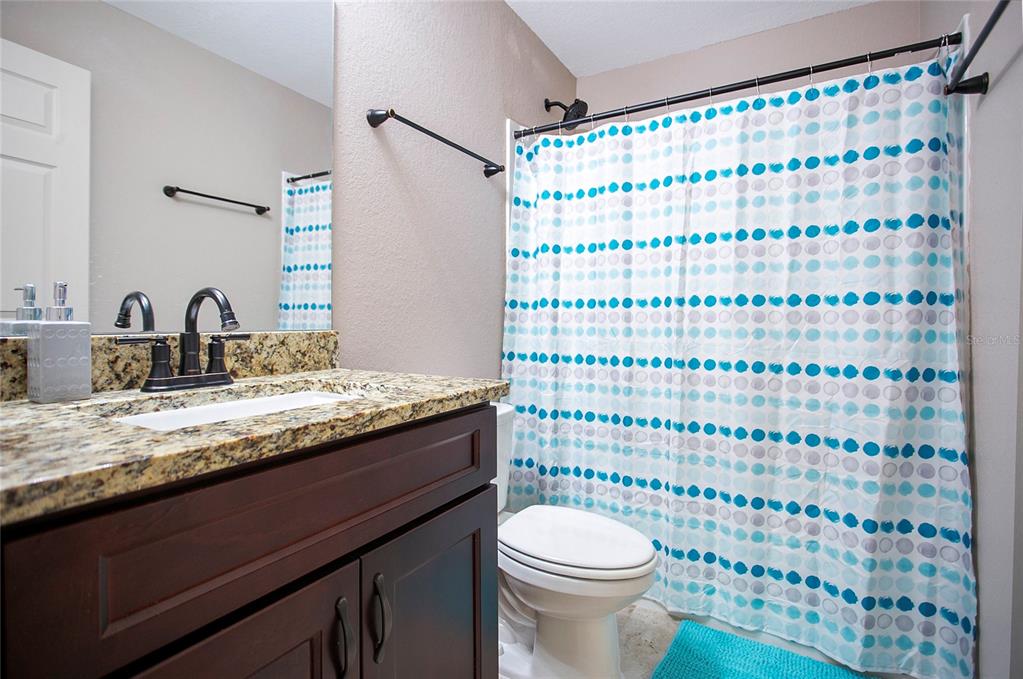 6949 Southwest 152nd Street Ocala, FL 34473 - Photo 13 of 20 a bathroom with a granite countertop sink a toilet and a shower