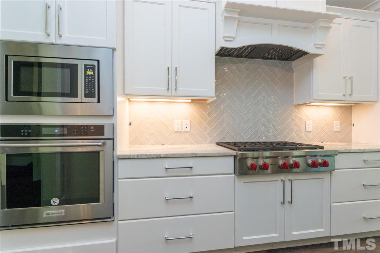 5000 Fanyon Way Raleigh, NC 27612 - Photo 5 of 25 Upgraded stacked cabinetry with range hood, WOLF gas cooktop and KITCHENAID Stainless Steel appliance package. Custom tile backsplash with subway tile in herringbone pattern.