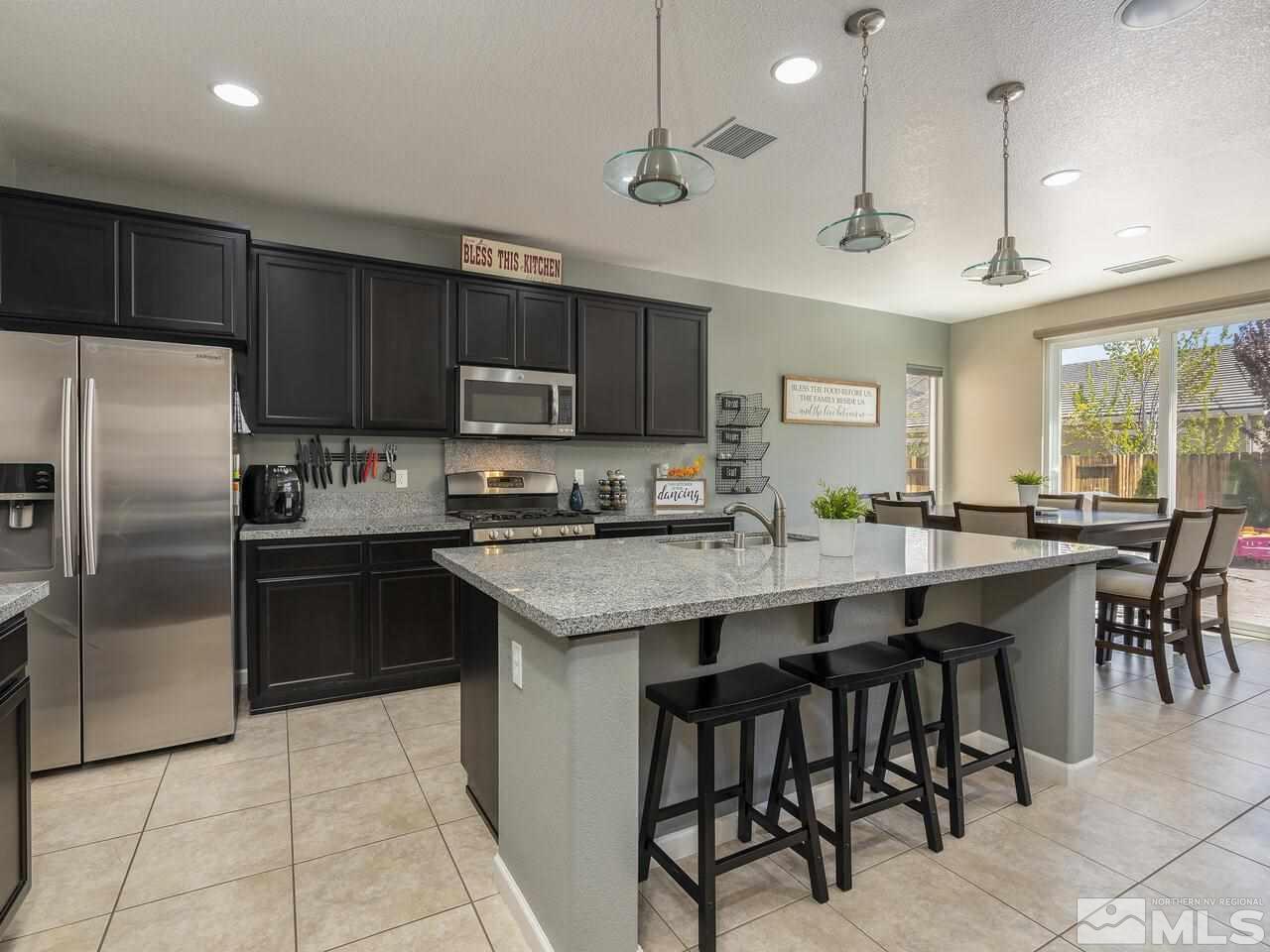 2090 Tawleed Road Reno, NV 89521 - Photo 8 of 24 a kitchen with kitchen island a refrigerator a stove a microwave oven a sink with a dining table and chairs