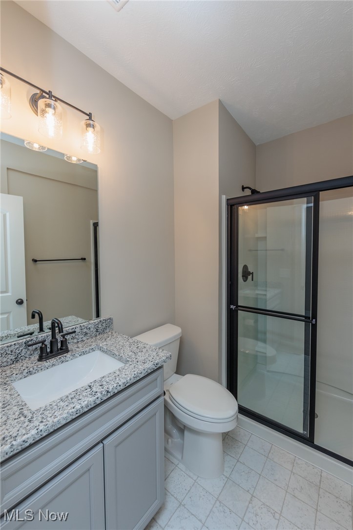36458 Appian Way North Ridgeville, OH 44039 - Photo 29 of 37 Bathroom with a textured ceiling, vanity, toilet, and walk in shower