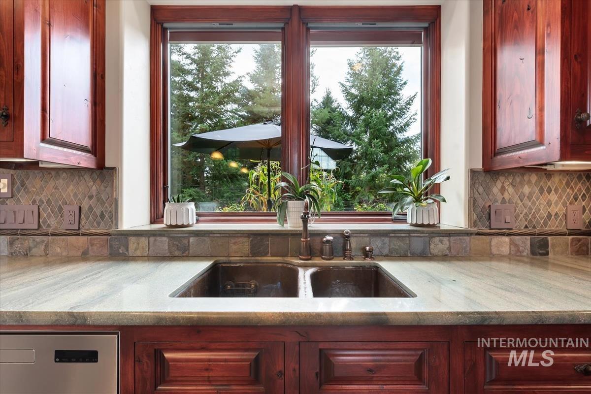 106 Hidden Hollow Road Hailey, ID 83333 - Photo 31 of 49 Wood-finish cabinetry, stone slab countertops, mosaic tile backsplash, double basin sink, and an integrated dishwasher