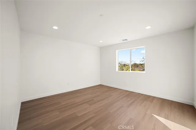 an empty room with wooden floor and window