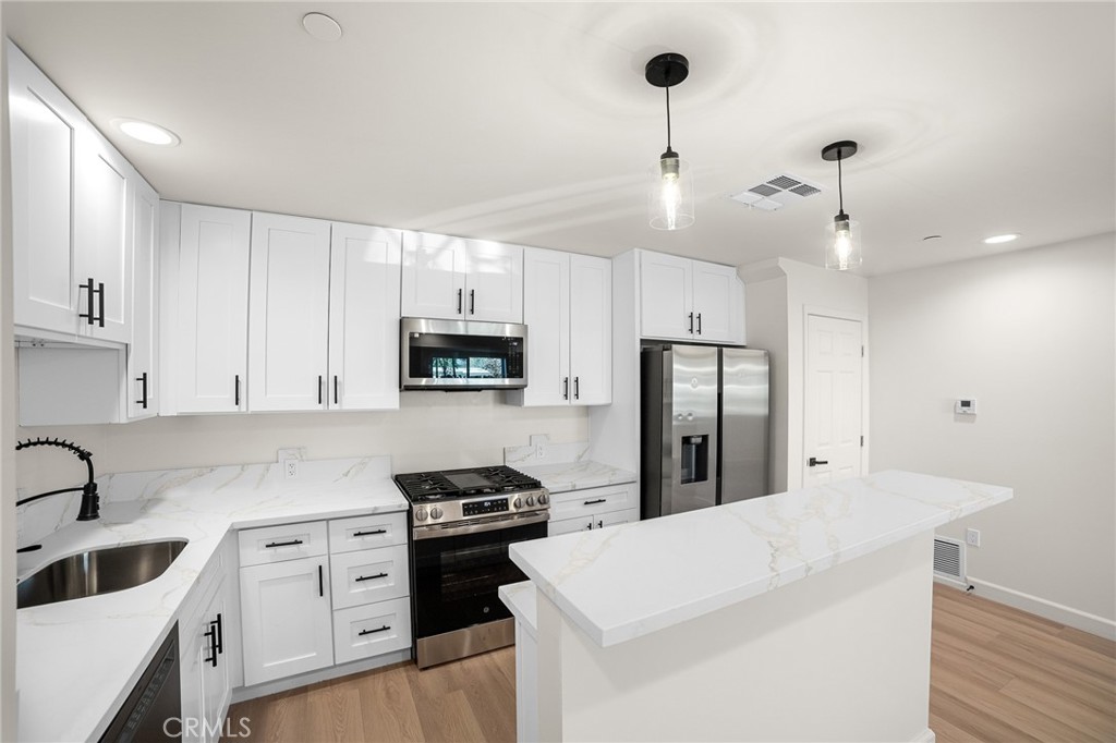 306 West Congress Street Colton, CA 92324 - Photo 9 of 28 a kitchen with white cabinets and stainless steel appliances