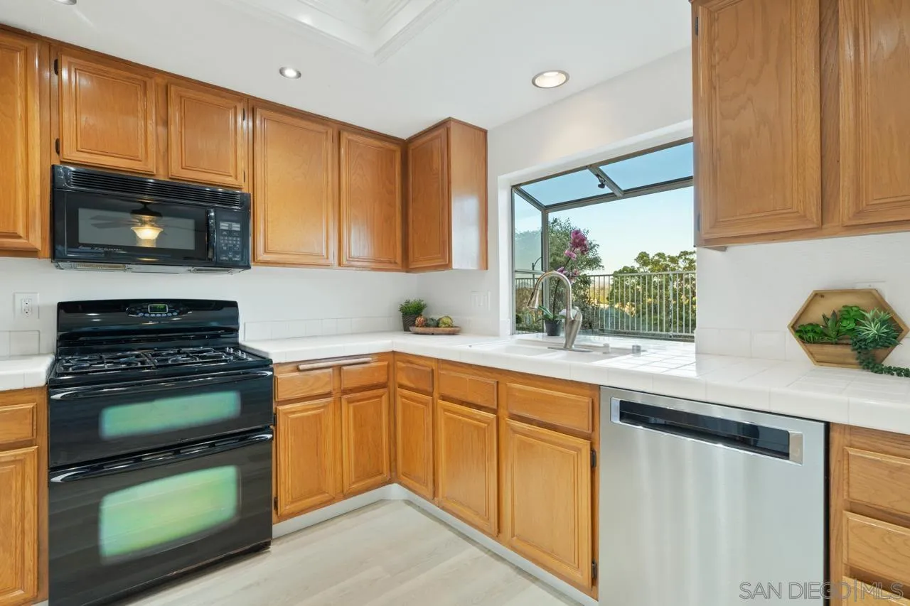 1904 Willow Ridge Drive Vista, CA 92081 - Photo 29 of 70 a kitchen with granite countertop wooden cabinets stainless steel appliances and a window