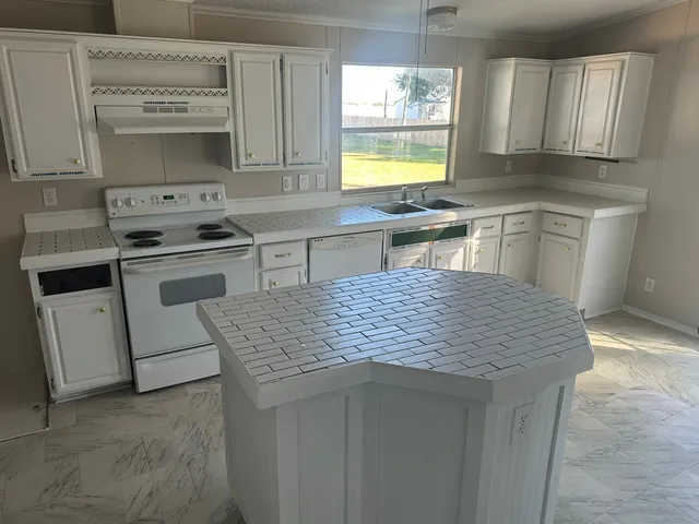 a kitchen with stainless steel appliances granite countertop a stove a sink dishwasher and a refrigerator