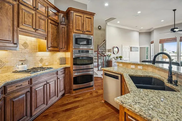 a kitchen with stainless steel appliances granite countertop a stove top oven a sink dishwasher and cabinets with wooden floor