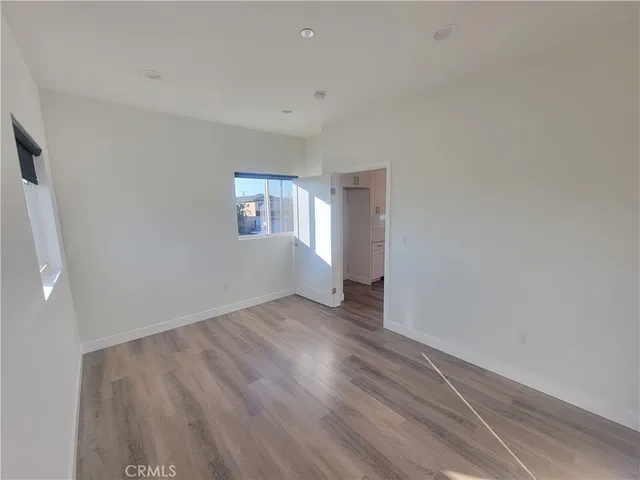 a view of a hallway with wooden floor and a bathroom