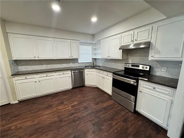 a kitchen with granite countertop white cabinets and white appliances