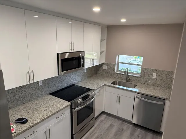 a kitchen with stainless steel appliances granite countertop a sink and a microwave