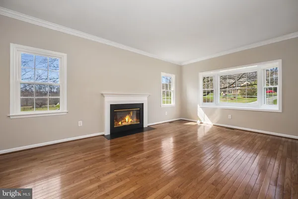 a view of an empty room with window and wooden floor