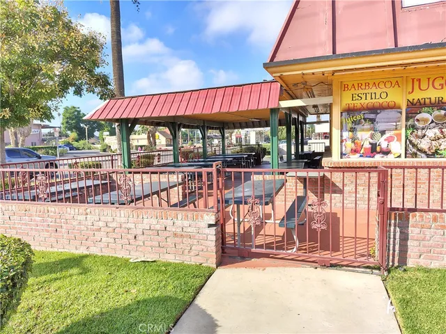a view of a patio with table and chairs under an umbrella with a small yard