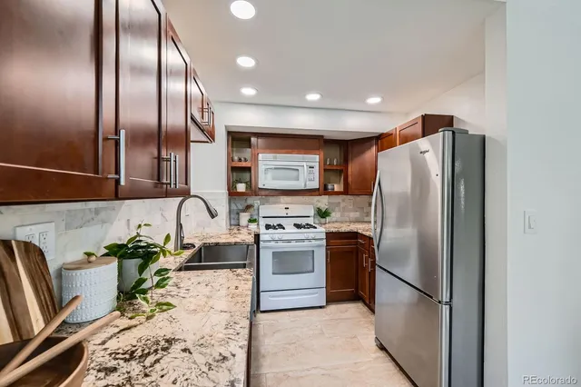 a kitchen with stainless steel appliances granite countertop a refrigerator a stove a sink and a refrigerator