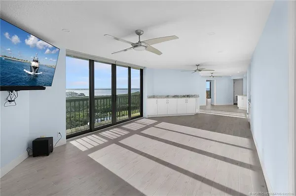 a large white kitchen with a sink a window and stainless steel appliances