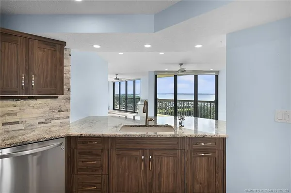 a kitchen with granite countertop a refrigerator and wooden cabinets