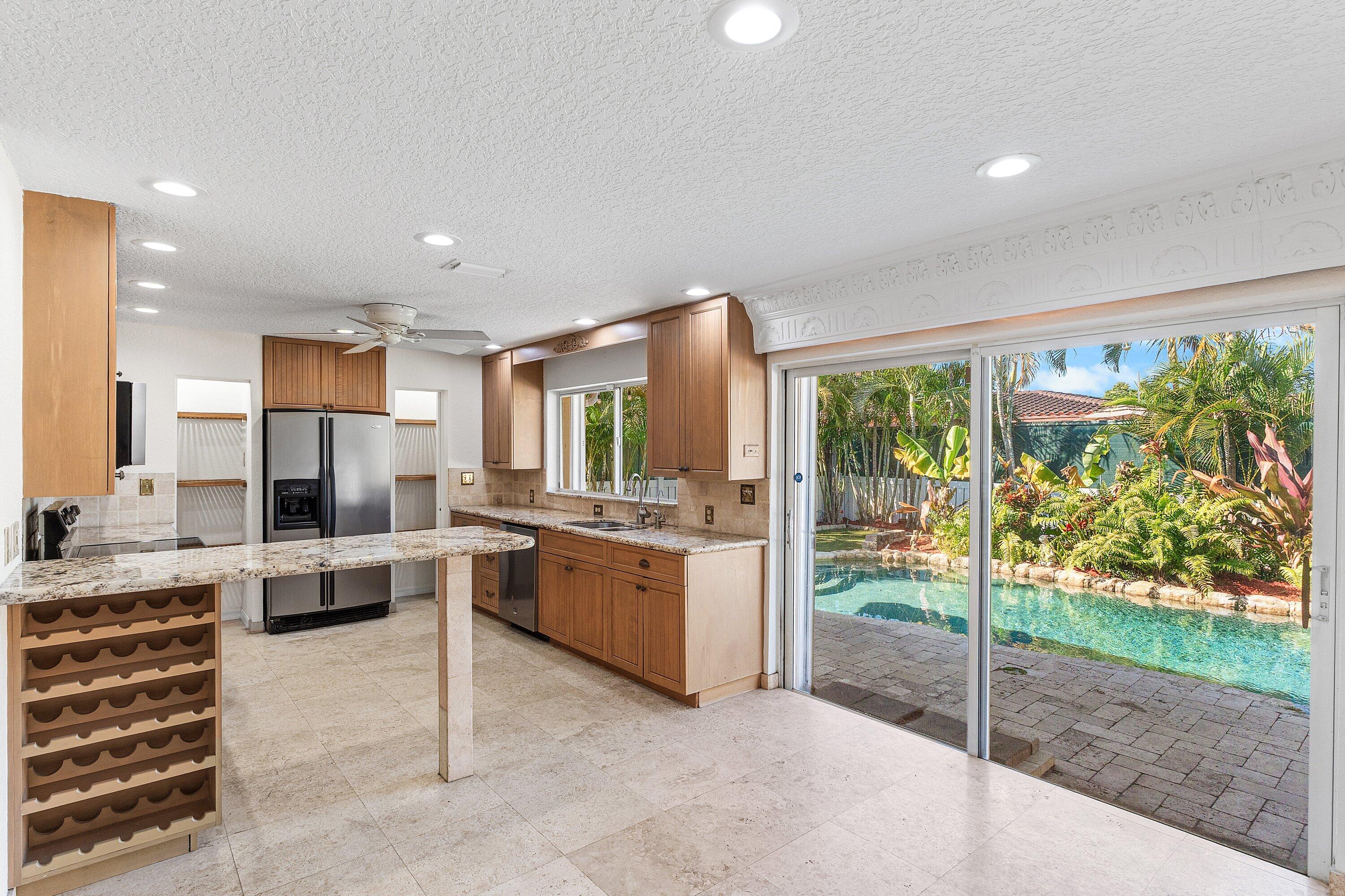 451 Northeast 25th Terrace Boca Raton, FL 33431 - Photo 12 of 47 a large kitchen with kitchen island a large window in it