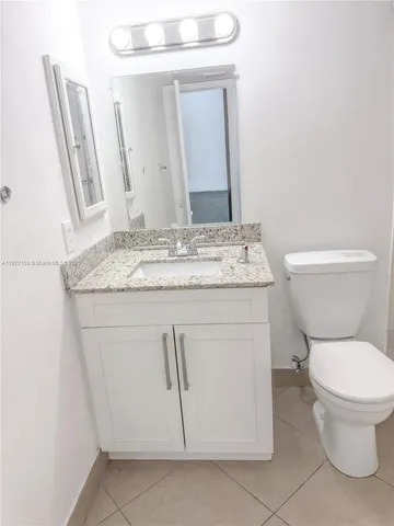 a bathroom with a granite countertop toilet sink and mirror