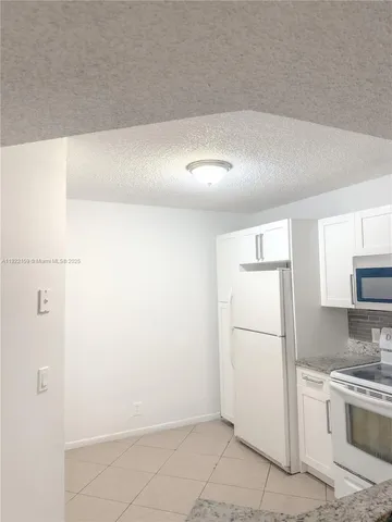 a kitchen with a refrigerator a stove top oven and white cabinets