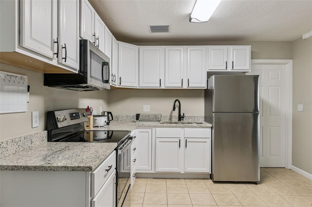 725 3rd Street Orange City, FL 32763 - Photo 6 of 15 a kitchen with stainless steel appliances granite countertop a refrigerator sink and cabinets