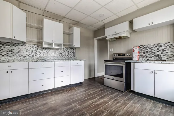 a kitchen with granite countertop white cabinets and white appliances