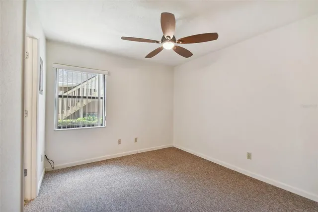 an empty room with windows and fan