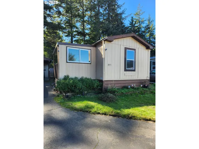 a view of a house with a yard plants and large tree