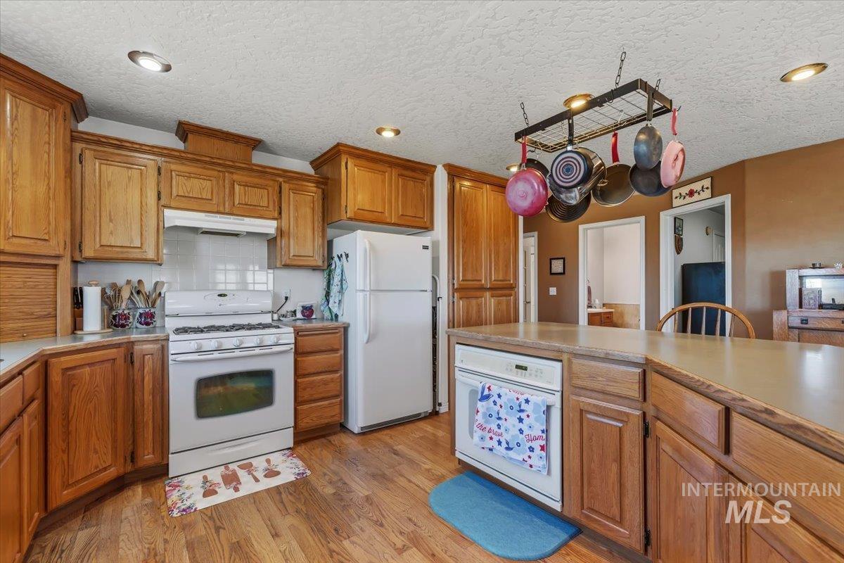 2331 Gulley Road Homedale, ID 83628 - Photo 13 of 46 Kitchen featuring wood-finish flooring, recessed lighting, wood cabinetry, a white gas range, and a white dishwasher