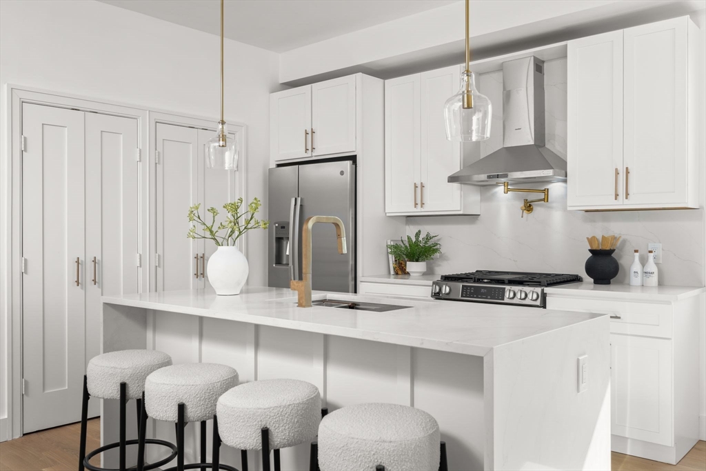 100 Bennington Street, Unit PH4A Boston, MA 02128 - Photo 2 of 41 a kitchen with stainless steel appliances kitchen island granite countertop a table chairs in it and wooden floors