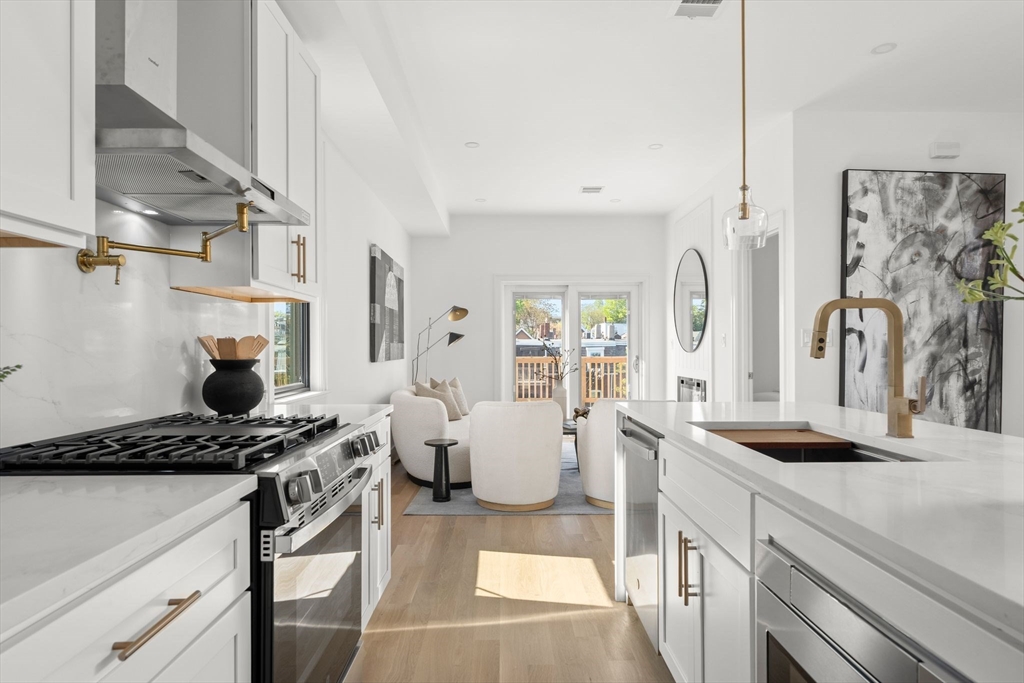 100 Bennington Street, Unit PH4A Boston, MA 02128 - Photo 5 of 41 a kitchen with stainless steel appliances kitchen island wooden cabinets a stove and a sink