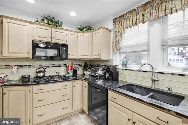 a kitchen with granite countertop white cabinets white stainless steel appliances a sink and window