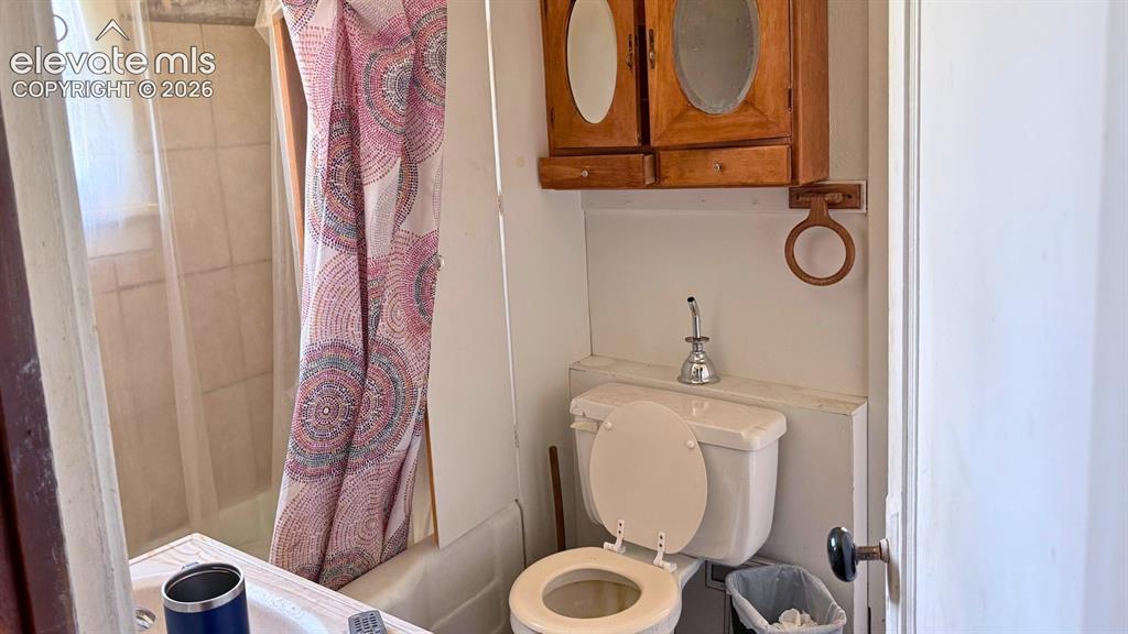 3380 Curtis Road Peyton, CO 80831 - Photo 7 of 13 Bathroom featuring a built-in tub with white tile surround, toilet, and wood-finish wall-mounted cabinetry