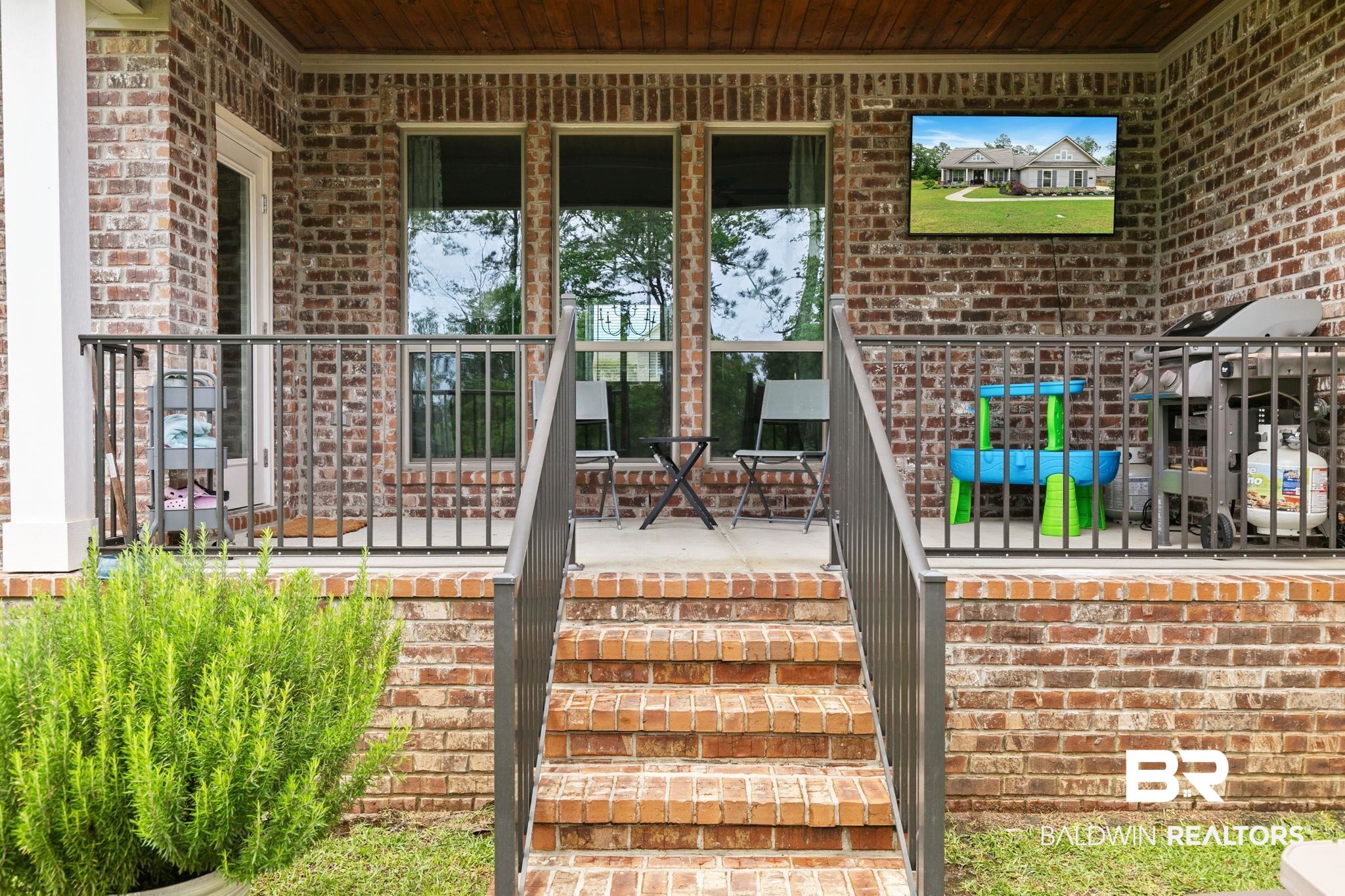 13233 Ibis Boulevard Daphne, AL 36527 - Photo 56 of 100 Brick exterior with covered patio featuring a dark wood-finish ceiling, three large windows, and a mounted display