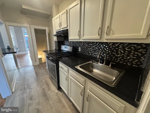 a kitchen with granite countertop white cabinets and black appliances
