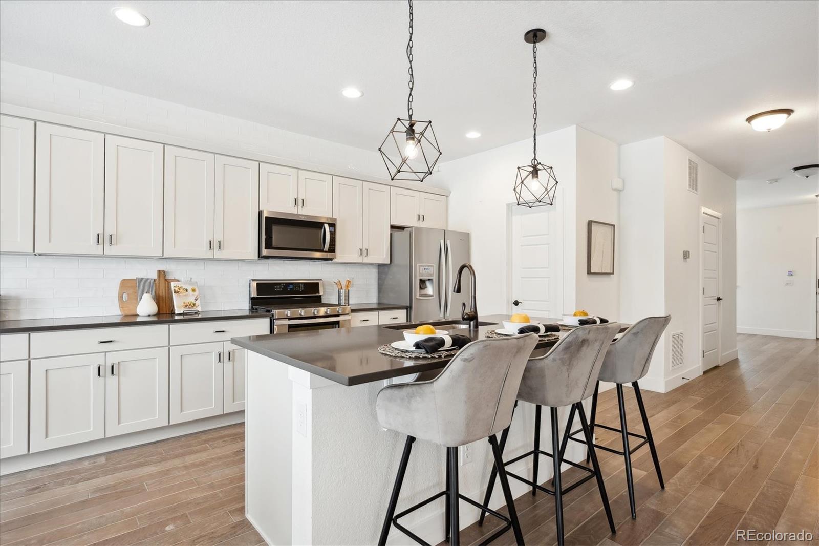 12841 Red Rosa Circle Parker, CO 80134 - Photo 5 of 29 a kitchen with stainless steel appliances granite countertop a stove a sink a refrigerator a microwave a island with white cabinets and wooden floor