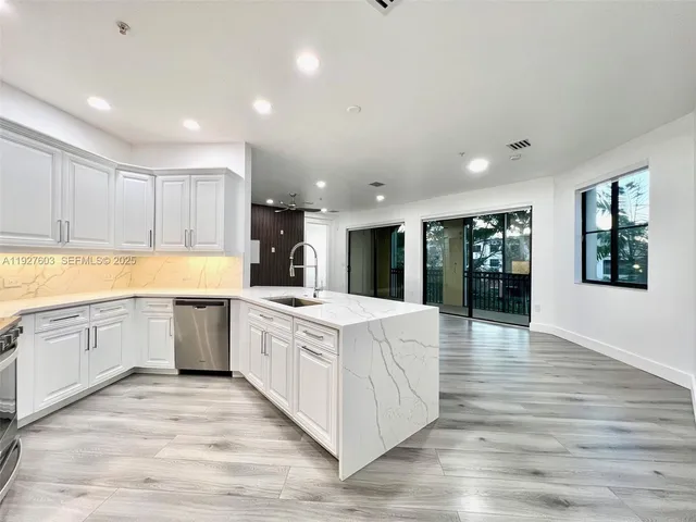 a large white kitchen with wooden floors and white cabinets