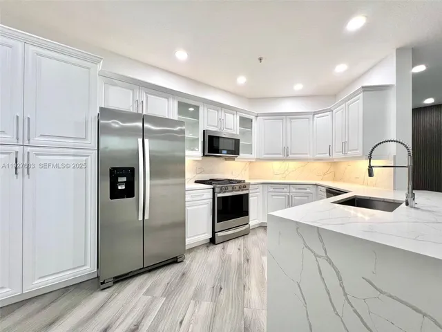a kitchen with granite countertop a refrigerator sink and cabinets