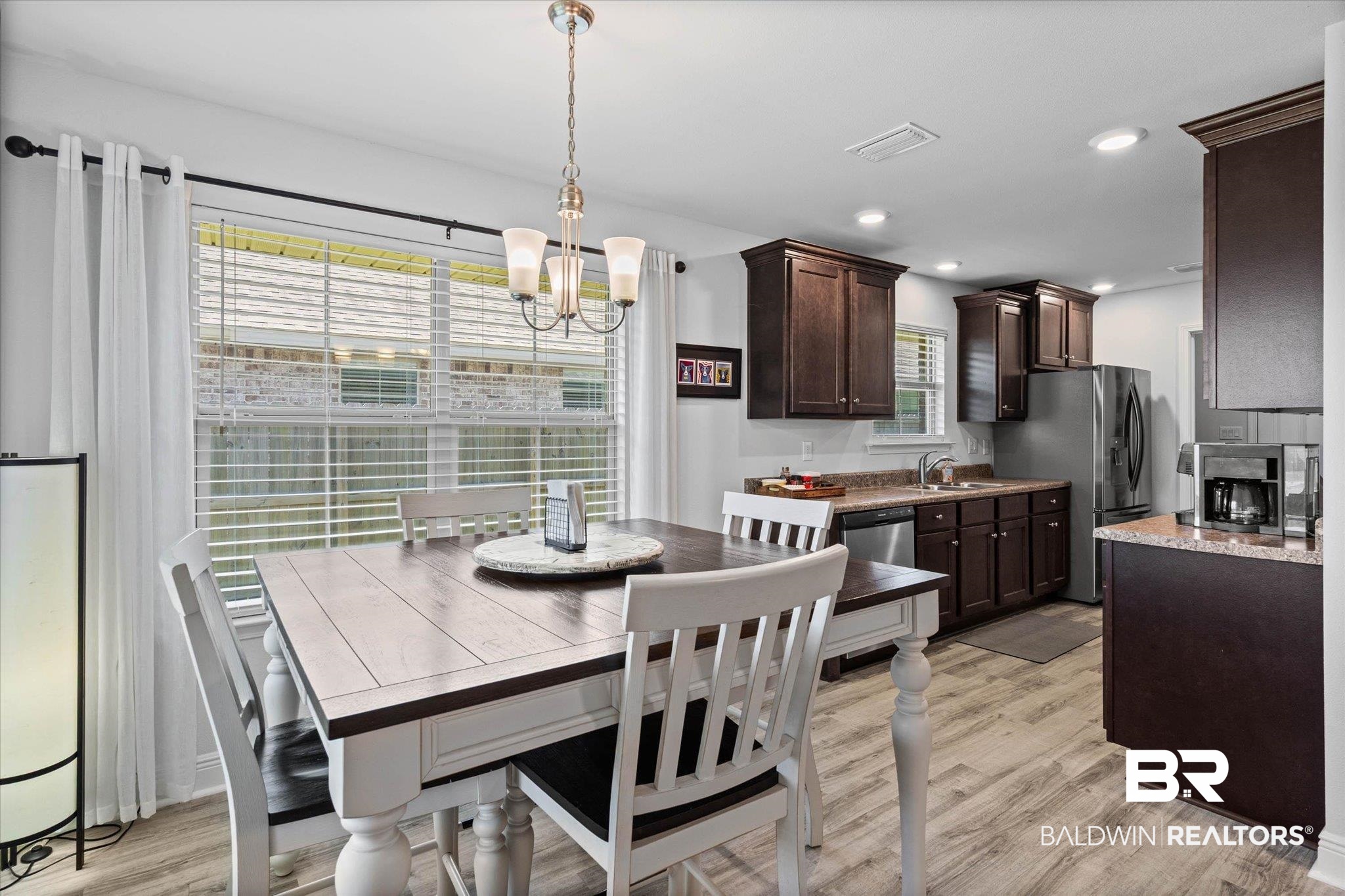 22420 Respite Lane Foley, AL 36535 - Photo 8 of 35 Open-concept kitchen and dining area featuring wood-finish flooring, recessed lighting, dark wood cabinetry, and a stainless steel dishwasher