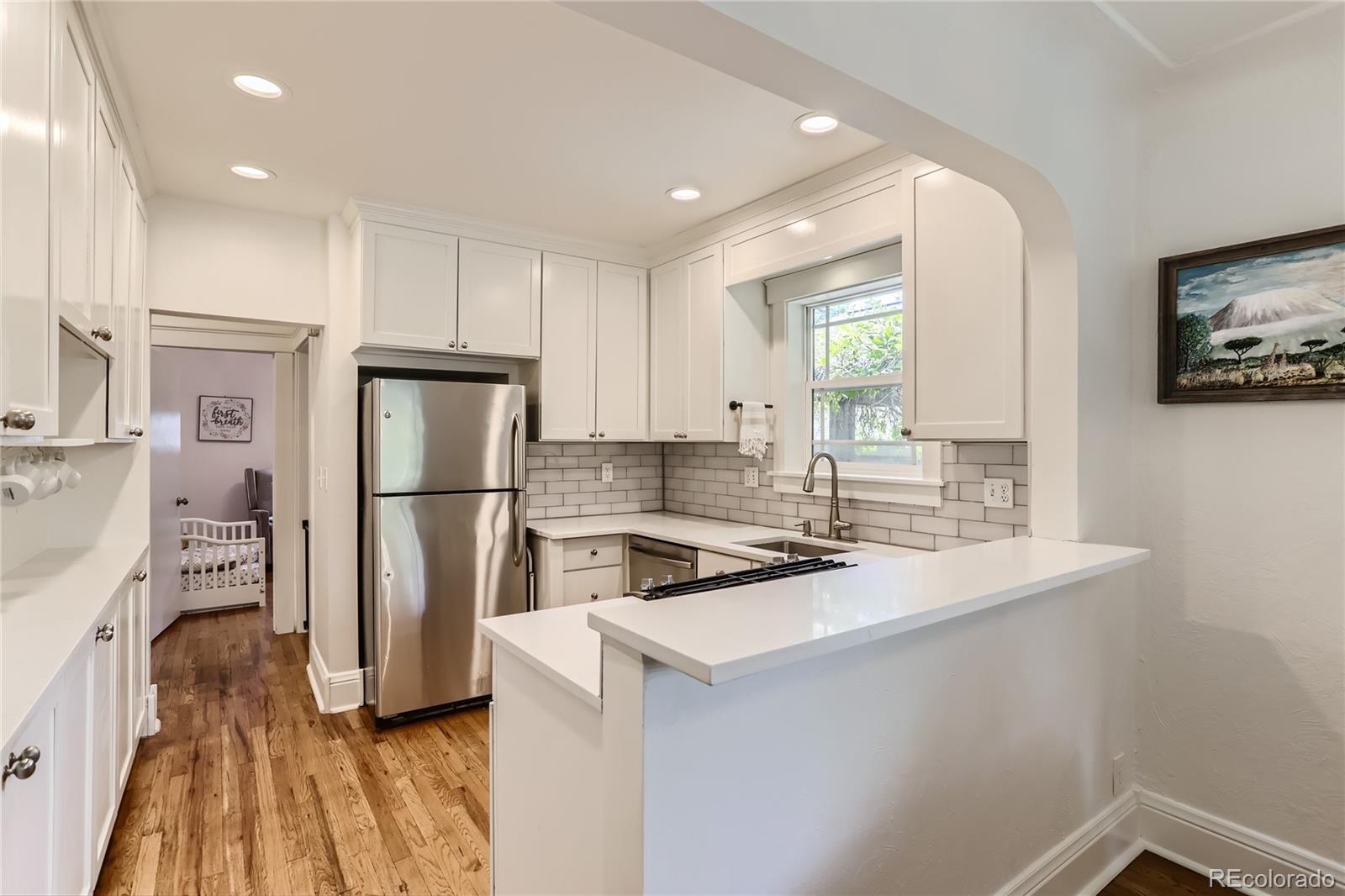 954 Monroe Street Denver, CO 80206 - Photo 11 of 28 a kitchen that has a refrigerator a stove a sink and a dining table with wooden floor