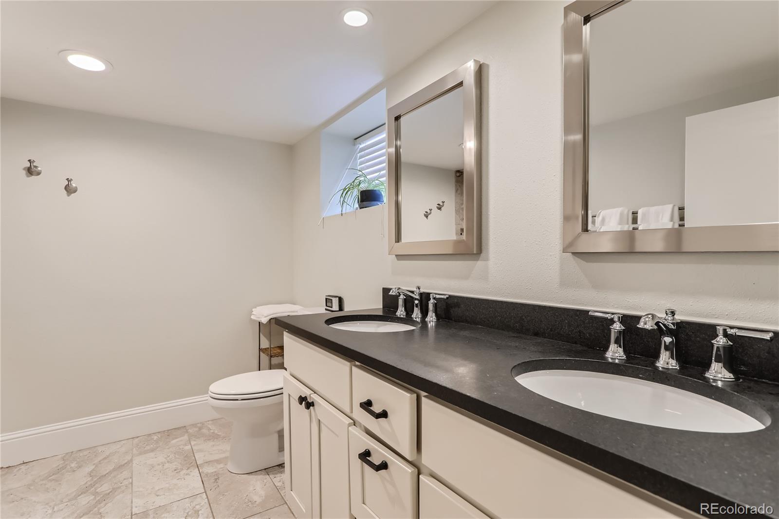 954 Monroe Street Denver, CO 80206 - Photo 23 of 28 a bathroom with a double vanity sink and a mirror