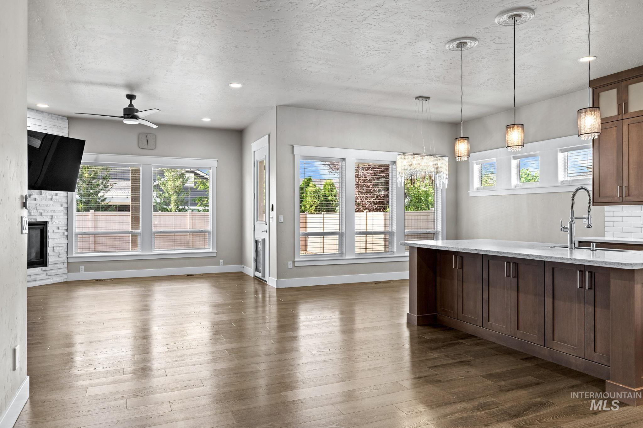 2934 East Murchison Street Meridian, ID 83642 - Photo 15 of 44 Open-concept living space featuring wood-finish flooring, a white brick fireplace, and extensive window sets