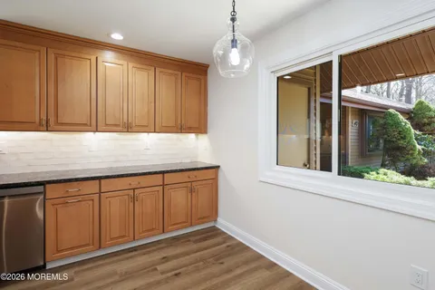 a kitchen with granite countertop wooden cabinets a microwave a sink and a window