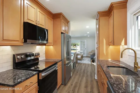a kitchen with granite countertop a stove a sink and a microwave