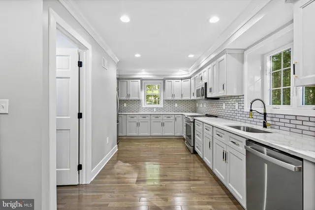 a large kitchen with stainless steel appliances granite countertop a sink and cabinets