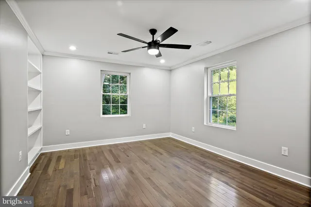 a view of empty room with wooden floor and fan