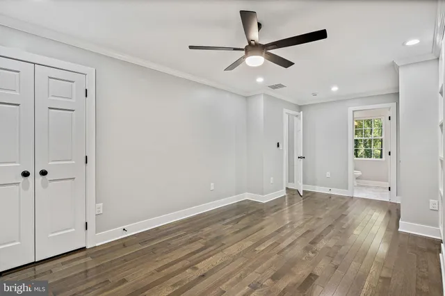 an empty room with wooden floor ceiling fan and windows
