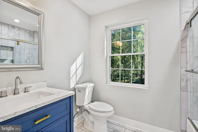 a bathroom with a granite countertop toilet sink and mirror