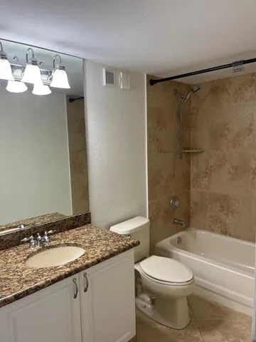 a bathroom with a granite countertop sink toilet and shower