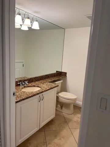 a bathroom with a granite countertop toilet and a sink