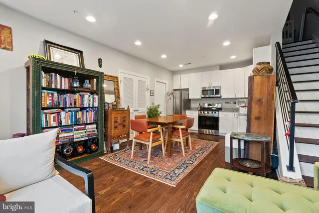 a kitchen with stainless steel appliances kitchen island granite countertop a refrigerator oven a sink dishwasher and white cabinets with wooden floor